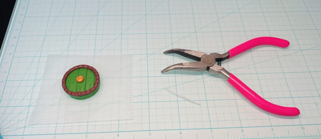 pair of jewelry pliers and polymer clay charm with thin 22 gauge silver wire