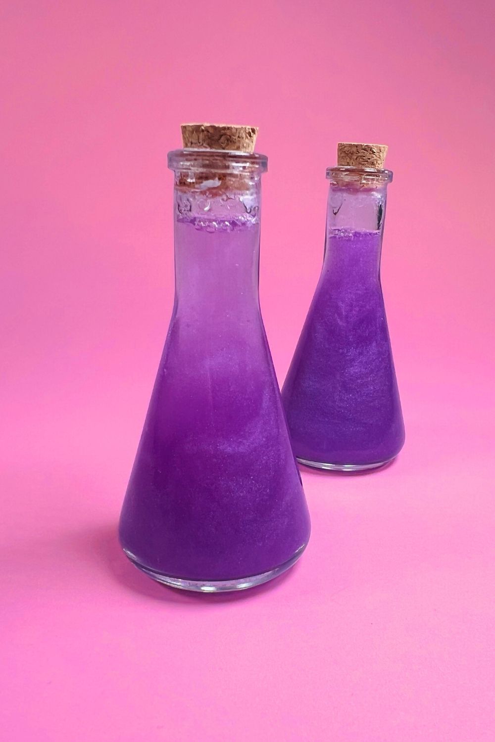 two full diy potion bottles with pretty homemade purple glitter potion 